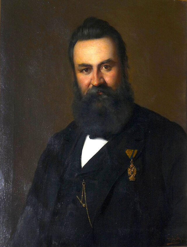 Ein Portrait-Gemälde, das einen Herren mit langem, dunklen Bart im Anzug zeigt.